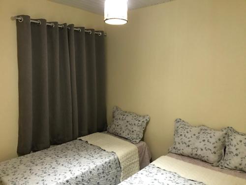 瓜鲁柳斯GA3-Hospedagem Próximo ao Aeroporto de Guarulhos的一间卧室设有两张床,窗户配有窗帘