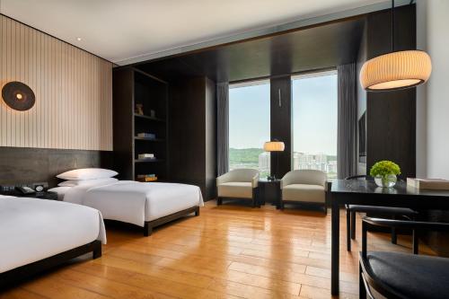 武汉武汉光谷凯悦酒店的一间卧室配有两张床和一张桌子及椅子