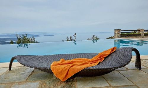 拉夫科斯Black Diamond Luxury Unique Villa Pelion的坐在游泳池旁椅子上的橙色毯子