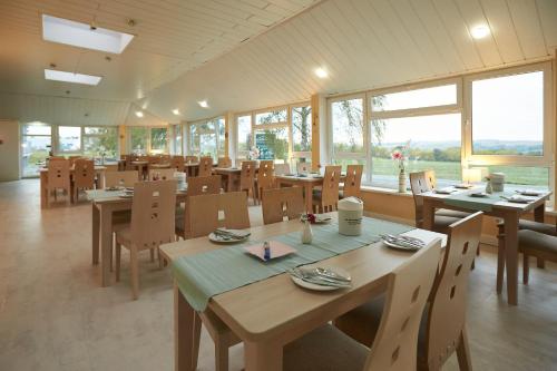 阿波尔达魏玛伯格酒店的餐厅设有木桌、椅子和窗户。