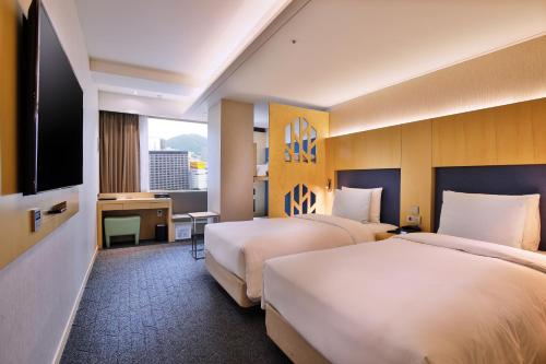 首尔Hotel Midcity Myeongdong的酒店客房设有两张床和一台平面电视。
