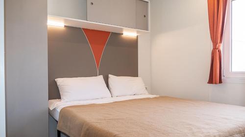 拉齐塞IdeaLazise Camping and Village的一张带白色枕头和橙色墙壁的床