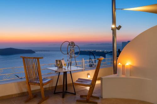 易莫洛林La Maltese Caldera Concept的阳台配有桌椅,享有海景。