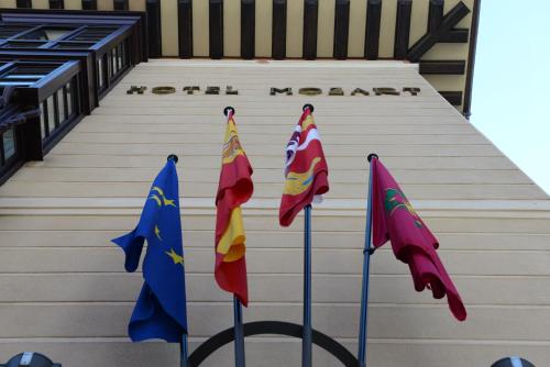 巴利亚多利德Hotel Mozart的建筑物前杆上的三面旗