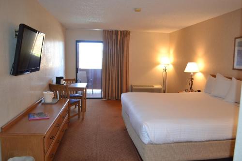 坎普维德The Lodge at Cliff Castle Casino的酒店客房配有一张床铺、一张桌子和一张书桌。