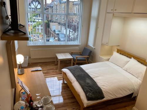 伦敦Chatsworth Guest House的一间卧室配有一张床、一张桌子和一个窗户。