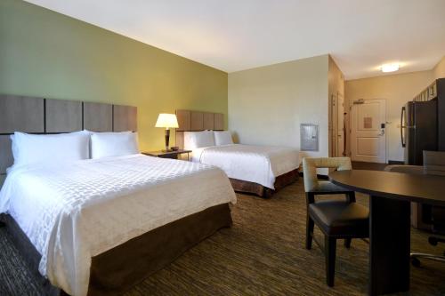 圣克莱尔斯维尔Candlewood Suites St Clairsville Wheeling Area, an IHG Hotel的酒店客房配有两张床和一张书桌