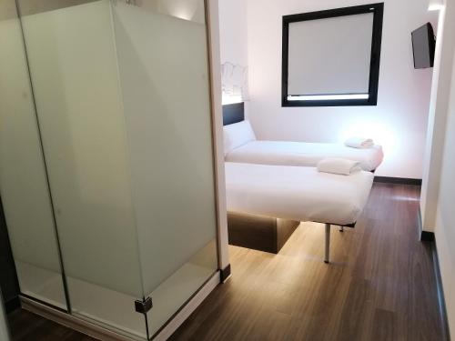 马拉加easyHotel Malaga City Centre的一间设有玻璃隔板、一张床和镜子的房间