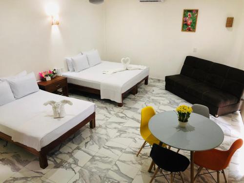 图卢姆Los Arcos Hotel - TULUM的客房设有两张床、一张沙发和一张桌子。