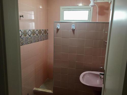 瓜鲁雅Apartamento PRAIA do TOMBO - Guarujá的粉红色的浴室设有水槽和窗户