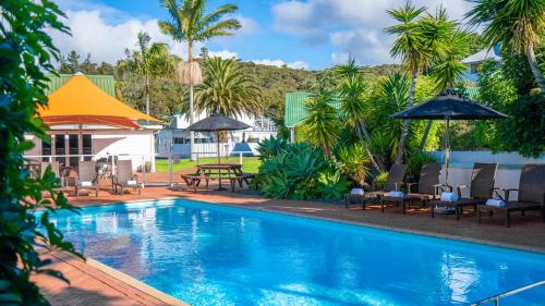 派西亚群岛海湾景区酒店的一个带桌椅和遮阳伞的游泳池