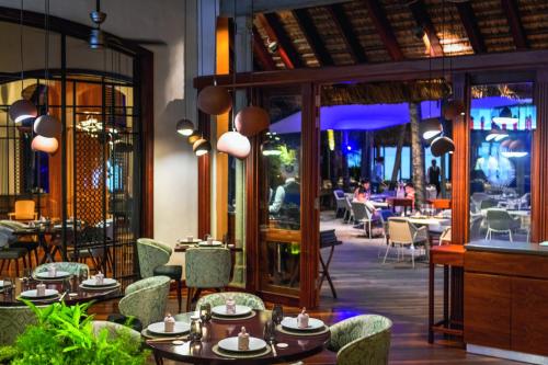 勒莫尔尼Dinarobin Beachcomber Golf Resort & Spa的一间带桌椅的用餐室和一间餐厅