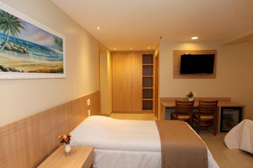 里约热内卢优雅普利亚酒店的酒店客房配有一张床、一张书桌和一台电视。