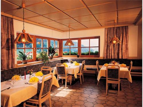 富内斯米特姆赫尔宾馆的餐厅设有白色的桌椅和窗户。