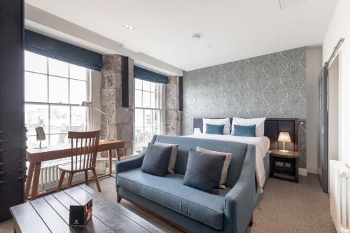 爱丁堡仕骅廷古城钱伯斯酒店公寓的一间卧室配有一张床和一张蓝色的沙发