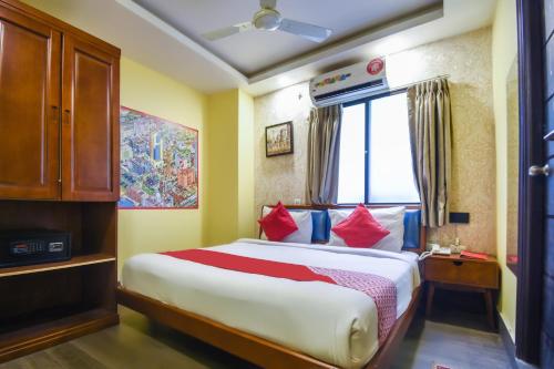 加尔各答Kiaan Inn的一间卧室配有一张带红色枕头的大床