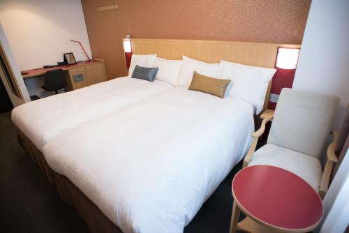 水户水户西山酒店的卧室配有一张白色大床和一把椅子