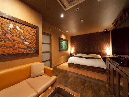 京都Hotel Grand Fine Kyoto Okazaki Heian Jingu Shrine的一间卧室配有一张床、一张沙发和一台电视。