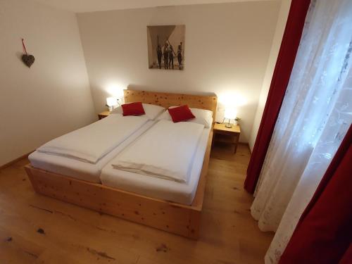 约赫贝格Apartment "Künstlhäusl"的一间卧室配有带白色床单和红色枕头的床。