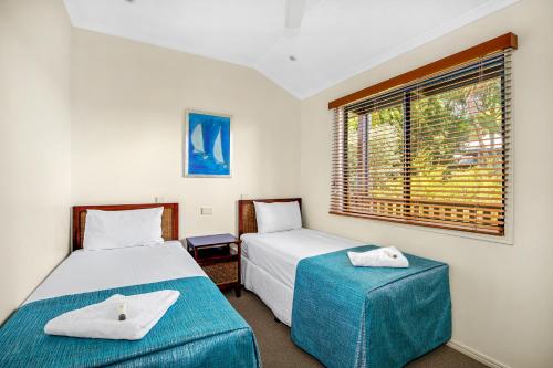 帝坎湾Tin Can Bay Marina Villas的一间卧室设有两张床和窗户。