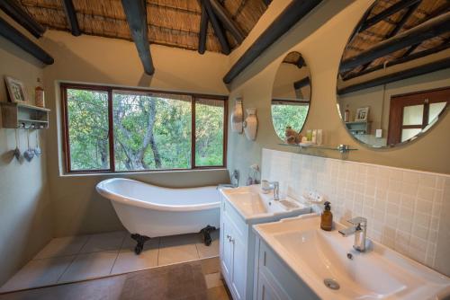 提姆巴瓦提禁猎区Kambaku Safari Lodge的带浴缸、两个盥洗盆和镜子的浴室