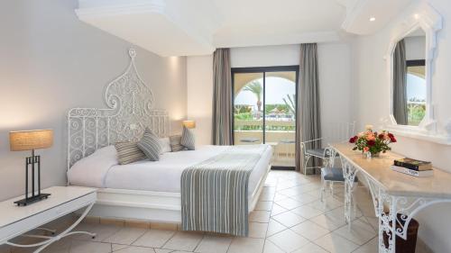 米多恩Djerba Aqua Resort的配有一张床、一张书桌和一扇窗户的酒店客房