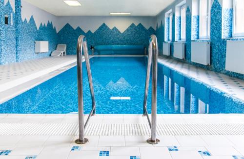 PapradnoHorský Hotel Podjavorník的室内游泳池拥有蓝色瓷砖墙壁