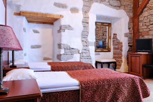 塔林圣奥拉沃酒店的一间卧室设有两张床和石墙