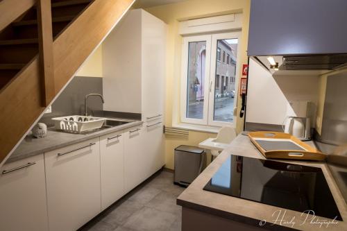 BassengeLes gîtes du Broukay - Alouette的厨房配有白色橱柜、水槽和窗户。
