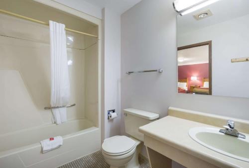 埃斯卡诺巴Econo Lodge Inn & Suites的浴室配有卫生间、盥洗盆和浴缸。