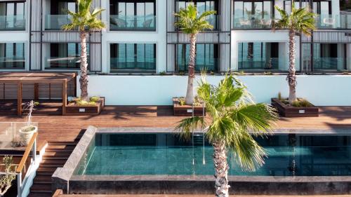 卡尔扎迈纳Mitsis Summer Palace的一座楼前种有棕榈树的游泳池