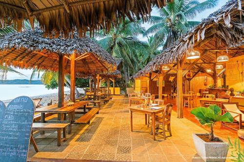 Ambaro萨姆巴特拉住宿加早餐旅馆的海滩上的餐厅,配有桌子和稻草遮阳伞