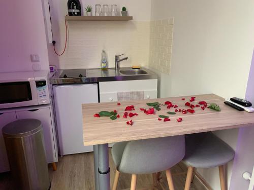 多勒Appartement Spa - NAHLEO Scandinave的厨房里摆放着红色鲜花的桌子
