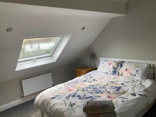 杜伦白宫小屋度假屋的一间卧室配有一张带花卉床罩的床和窗户。