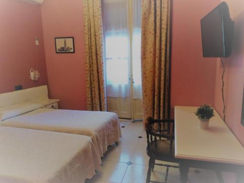 塞哥维亚Hostal Don Jaime I y II的酒店客房设有两张床、一张桌子和一个窗户。