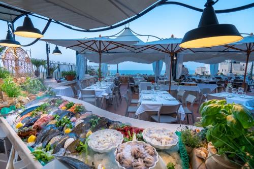 滨海波利尼亚诺萨拉森尼科沃酒店的在以海洋为背景的餐厅里享用自助餐