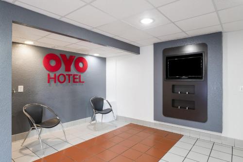 休斯顿OYO Hotel Houston Katy Freeway的酒店客房设有两把椅子和墙上的电视