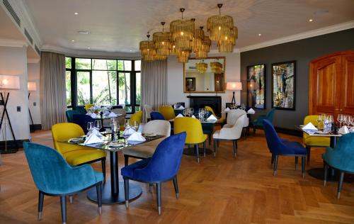 比勒陀利亚Apogee Boutique Hotel & Spa的餐厅设有蓝色和黄色的椅子和桌子