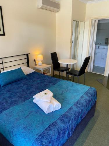 天鹅山明轮船汽车旅馆的一间卧室配有蓝色的床和桌椅