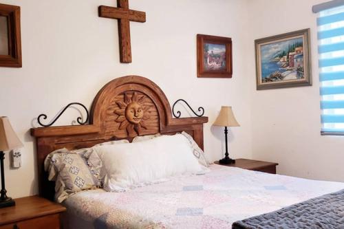 蒙特雷La Finca的一间卧室设有木制床头板,墙上有十字架