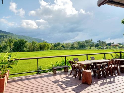 黎府ชมวิว รีสอร์ท的木甲板配有桌椅和绿色的田野