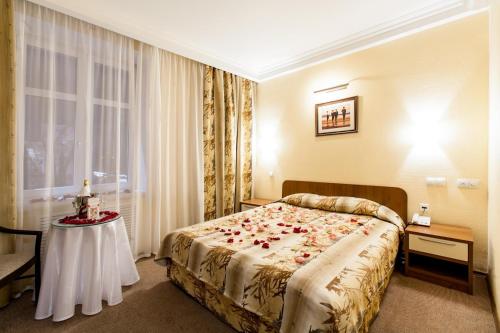 新古比雪夫斯克Hotel Retro的酒店客房设有一张床和一张玫瑰花桌