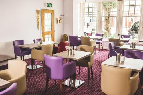 彼得伯勒The Queensgate Hotel的一间带桌子和紫色椅子的用餐室