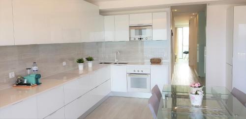 波瓦-迪瓦尔津Avenida dos Banhos Apartment的厨房配有白色橱柜和玻璃桌