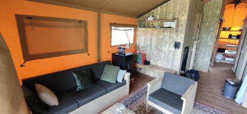MortierLe Relais d'Artagnan - relais équestre的客厅配有黑色沙发和橙色墙壁