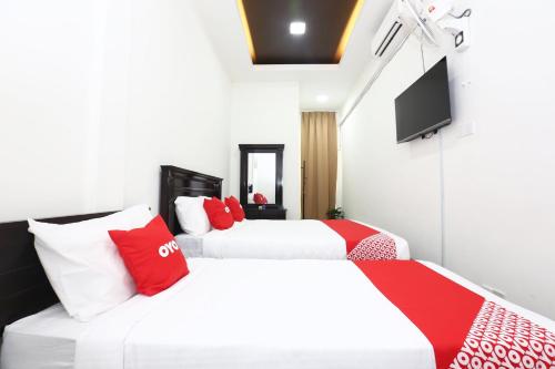 瓜拉丁加奴Super OYO 89678 Ady Hotel的两张带红色和白色枕头的床