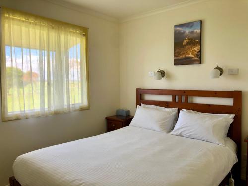 雅纳基普罗姆山丘小屋酒店的卧室配有一张大白色床和窗户