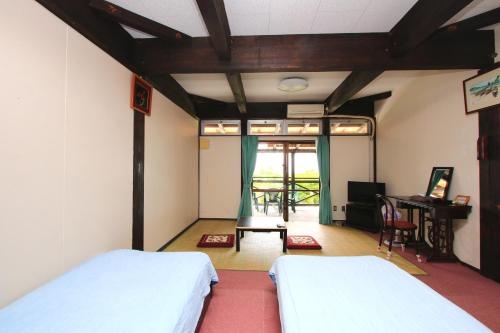 本部九州风之丘旅馆的一间卧室配有两张床、一张桌子和一张书桌