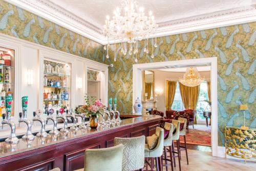 科克Cork's Vienna Woods Hotel & Villas的餐厅设有1间带椅子和吊灯的酒吧