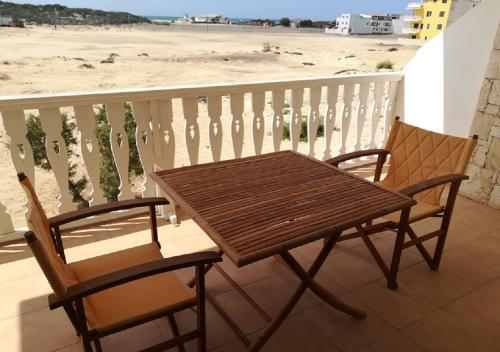 萨尔雷Apartments Mistral Estoril Beach的海滩阳台配有一张木桌和两把椅子
